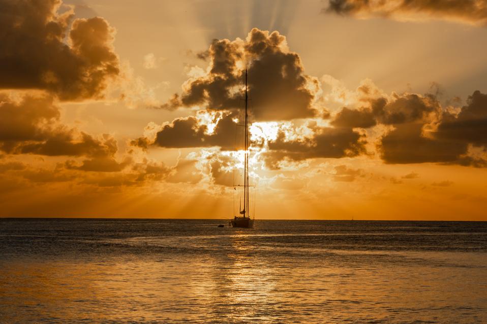 Sailing-Stream.fr ⚓ Naviguez dans les Caraïbes cachées ⚓ Coucher de soleil vue de yacht ancré dans le lagon, la baie de Britannia, l'île Mustique, Saint-Vincent-et-les Grenadines, mer des Caraïbes