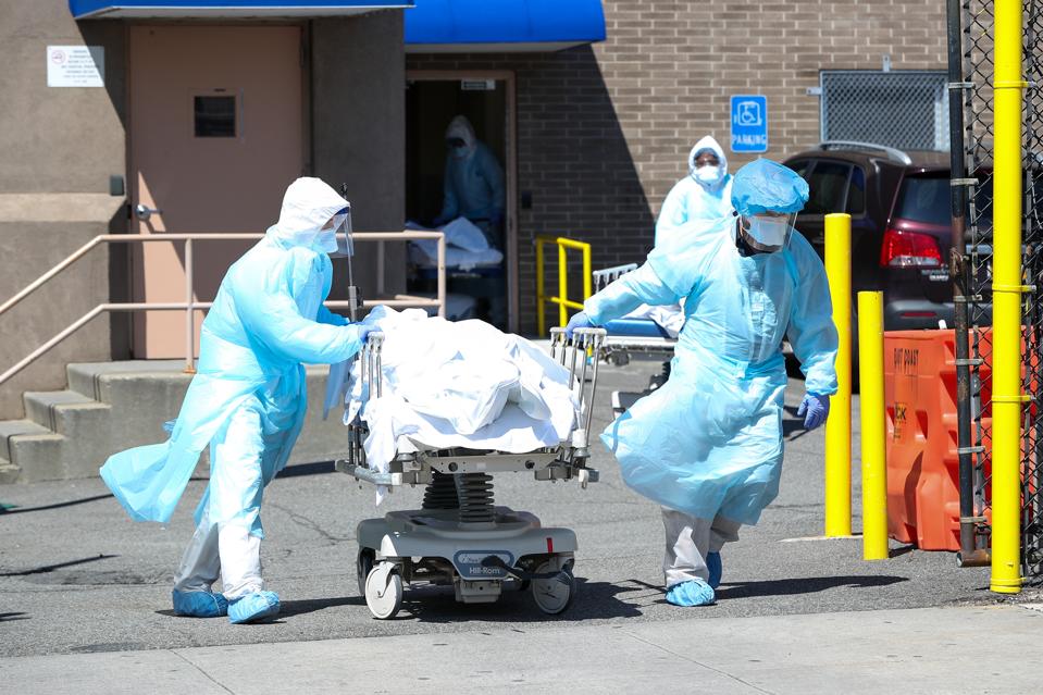 Healthcare workers transfer the corpse of a coronavirus victim to one of the container morgues by ... [+] TAYFUN COSKUN/ANADOLU AGENCY VIA GETTY IMAGES