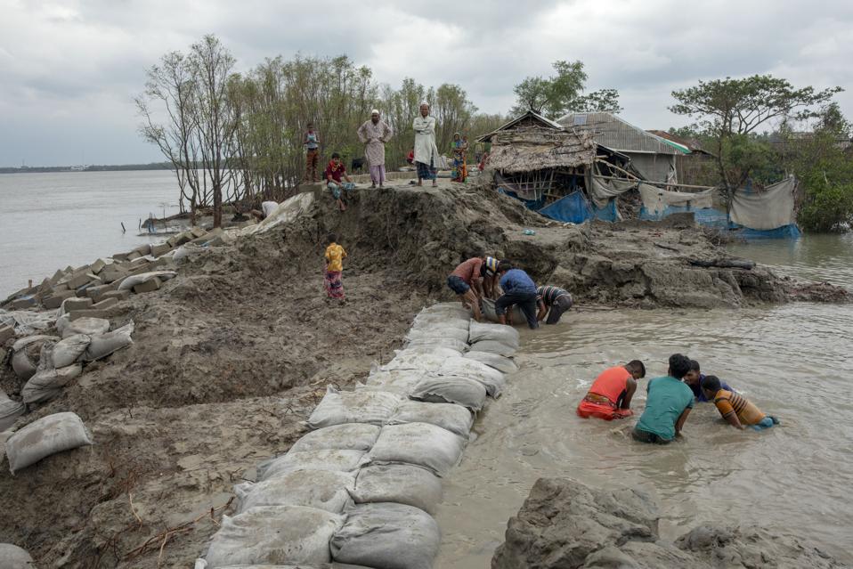 Village people try to repair the broken dam after the...