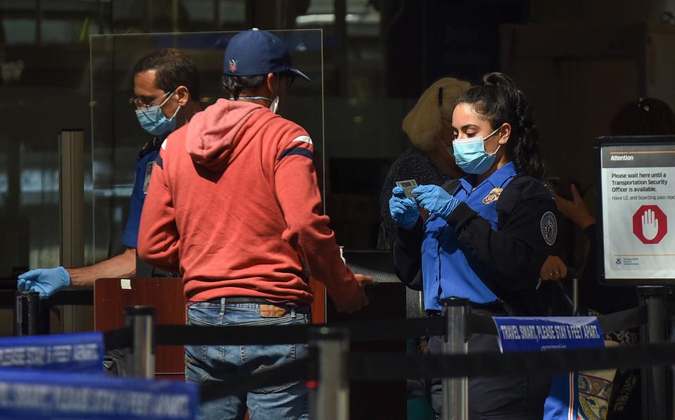A TSA officer checks a man's ID at a screening checkpoint at...