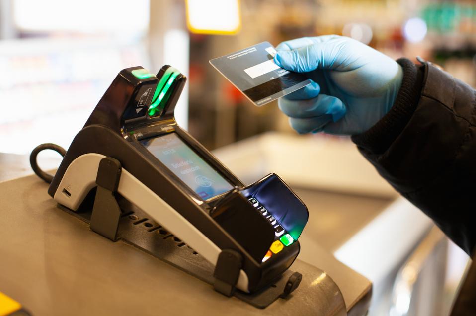 Man making a cashless payment at supermarket, wearing protective gloves