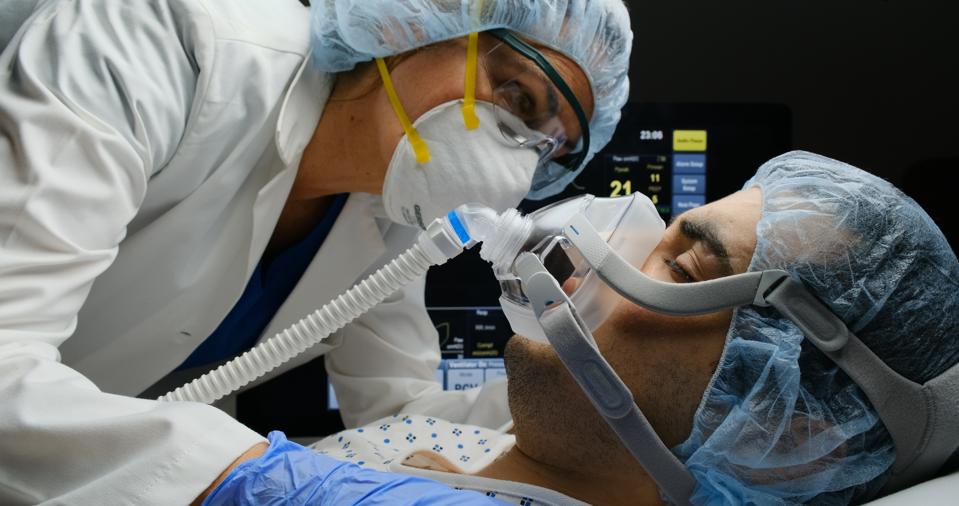 Female doctor checking on Covid-19 infected patient while connected to a ventilator