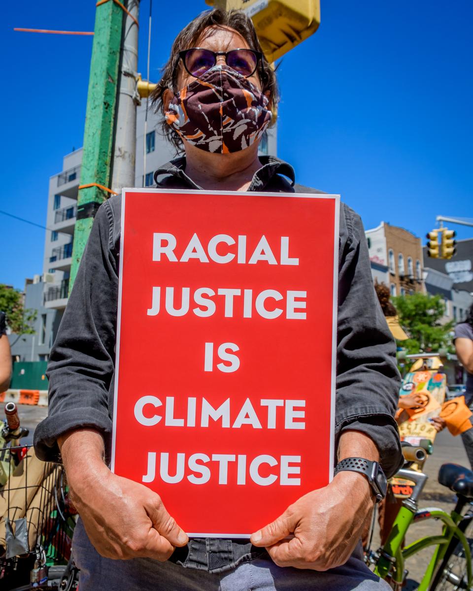 Protester holding a sign reading Racial Justice Is Climate...