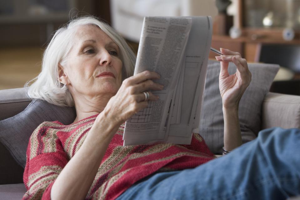 Elderly woman doing newspaper crossword puzzle