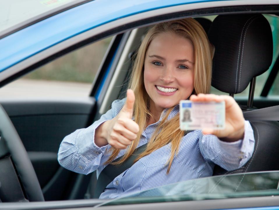 Attractive woman in car showing her drivers license