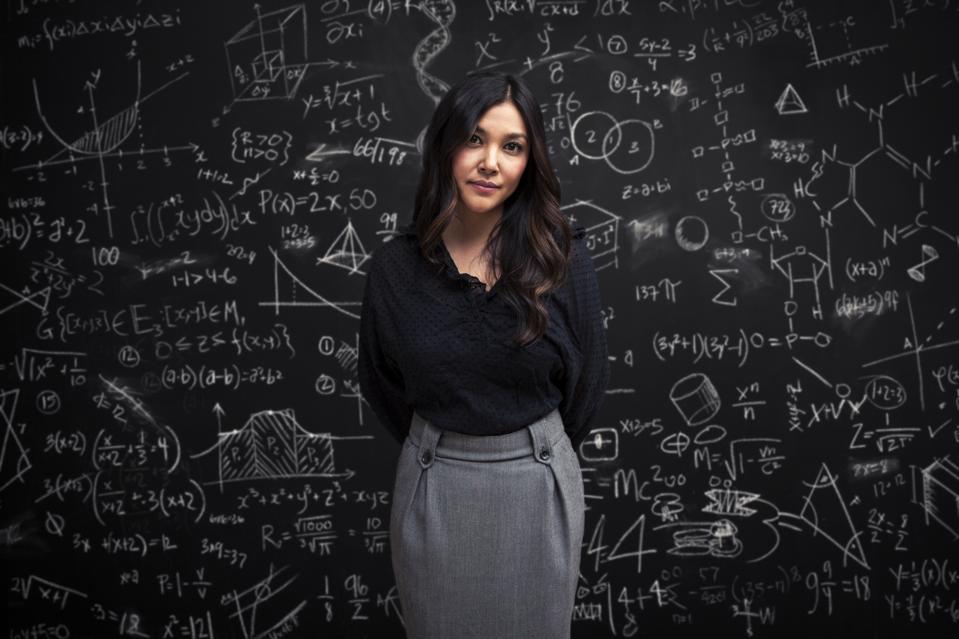 Woman stands calm in front of math chalkboard