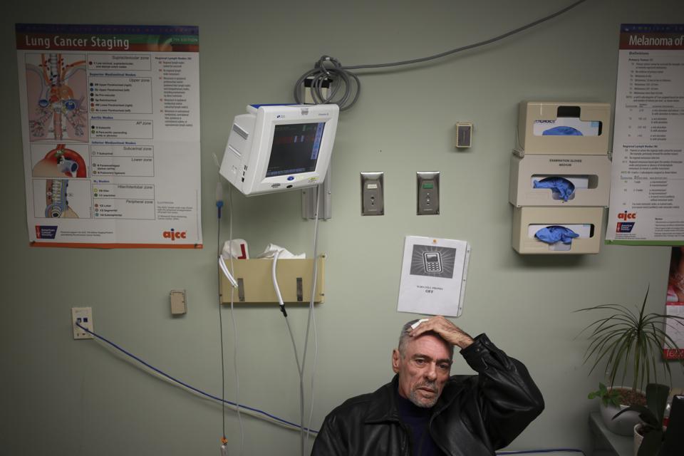 Cancer patient Tom Galjour sits in a waiting room during an appointment with his oncologist
