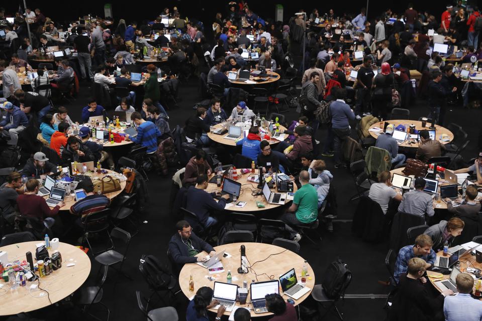 Attendees sit round tables and working on laptop computers participating in the TechCrunch Disrupt... [+] London 2015 Hackathon in the UK, December 5, 2015. The annual conference sees tech start-ups launch products and services competing in front of venture capital investors. (Photo: Luke MacGregor/Bloomberg).