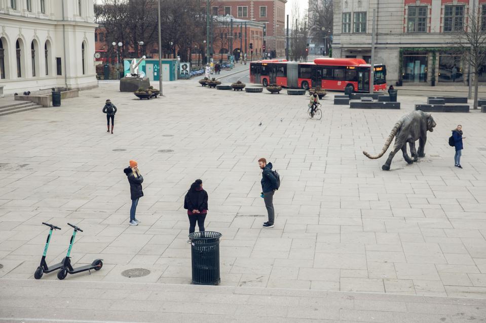 السكان المحليون الذين يتحدثون في ساحة Jernbanetorget في أوسلو يبقون على مسافة آمنة.