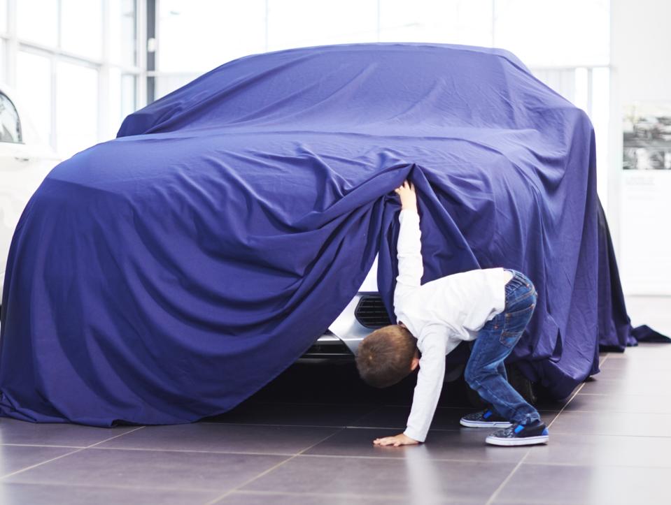 Boy at car dealer unveiling tarpaulin