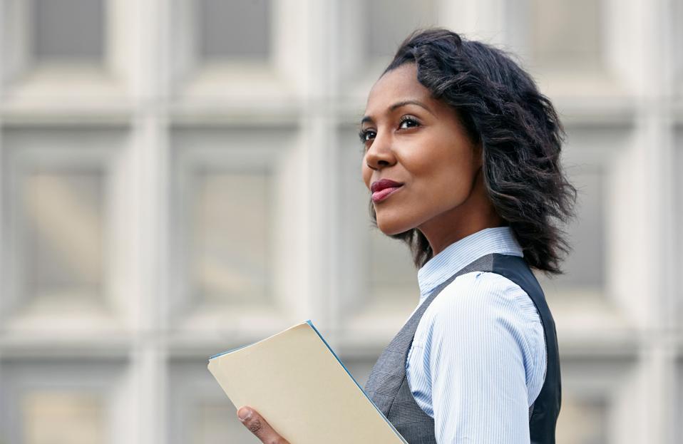 Portrait of young business woman holding paper work, looking away, side view