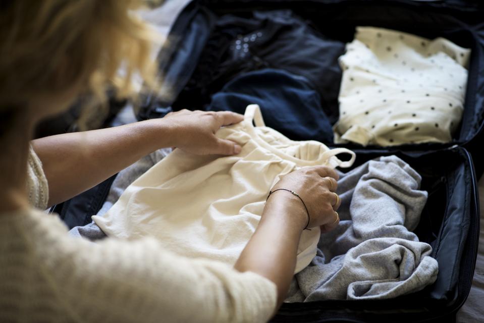 Closeup of womans hands packing suitcase