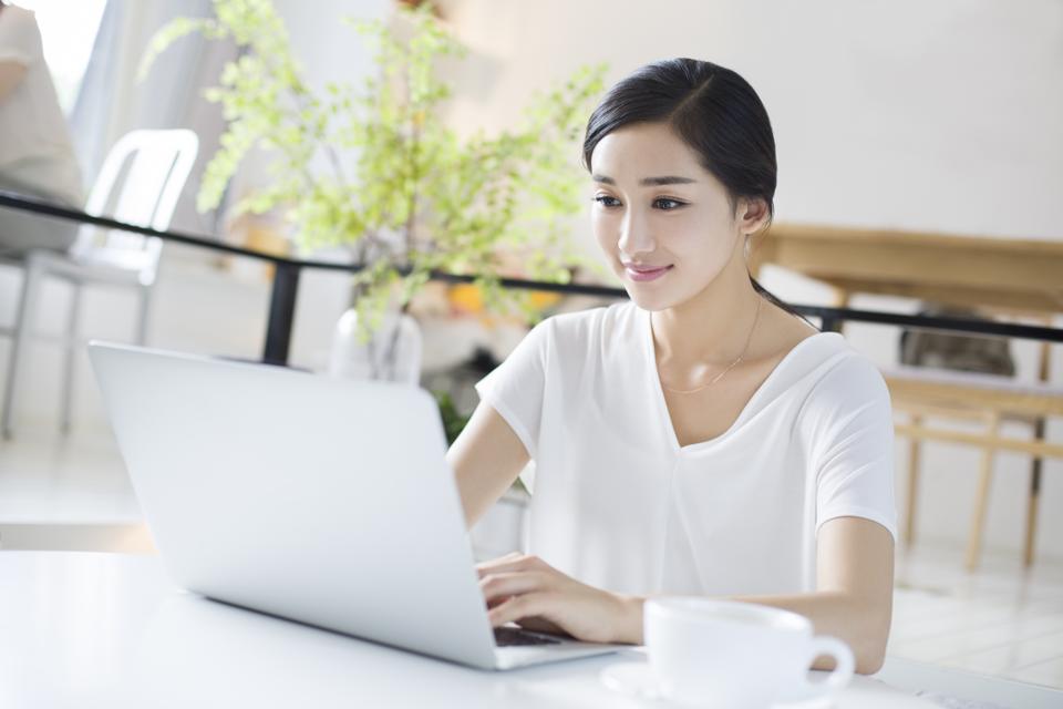 Happy young woman using laptop in coffee shop