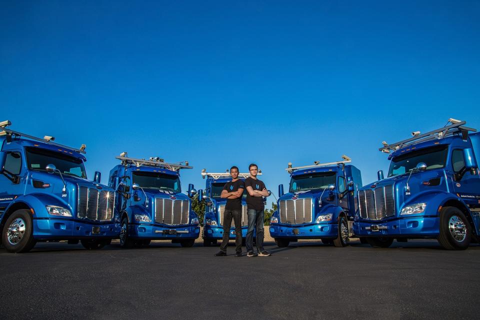 Embark co-founders Alex Rodrigues, left, and Brandon Moak with their fleet of autonomous semi-trucks at the startup's operations center in Ontario, California.