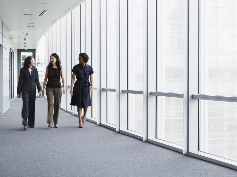 Businesswomen walking in hallway, smiling, portrait