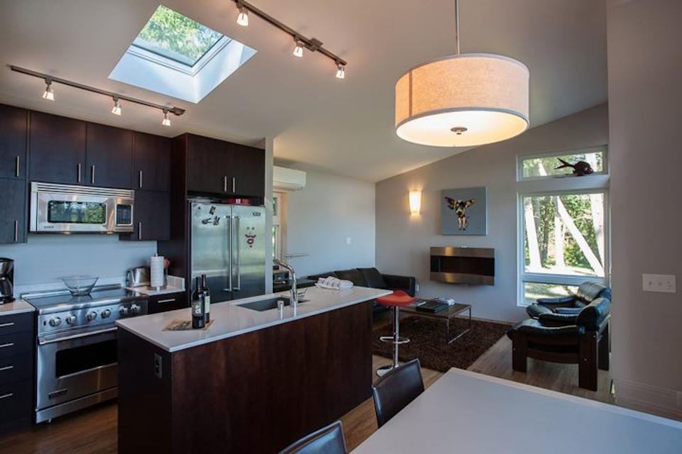 Kitchen in a tiny house. Dark cabinets and white countertop and a skylight.