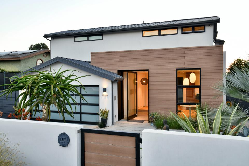 A modern looking home with clerestory windows under the eaves, wood facade, large, windows and a translucent garage door.