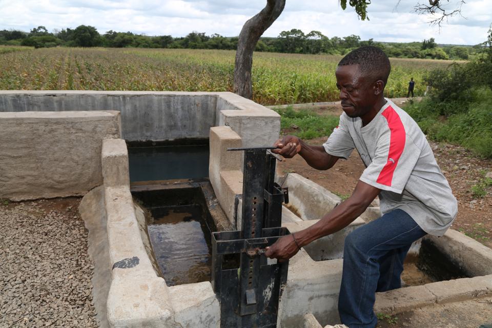 A man crouches over an irrigation device