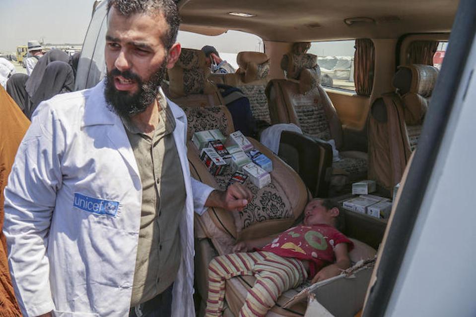 Sinusuri ng isang manggagawa sa kalusugan ng UNICEF ang isang may sakit na bata sa isang mobile health unit sa kampo ng Al-Hol sa Syria noong Hulyo 2019.