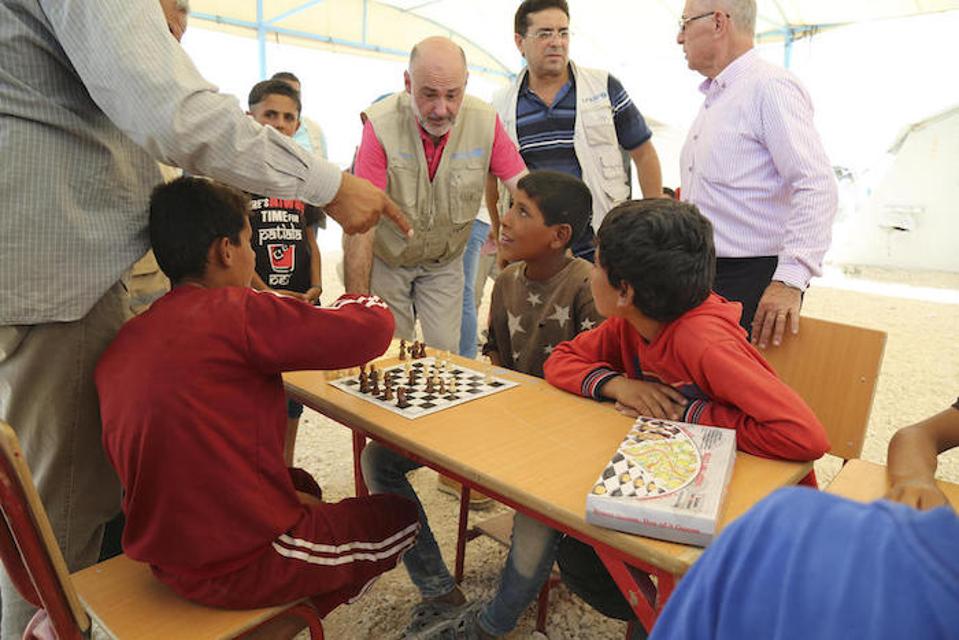 Ang kinatawan ng UNICEF sa Syria Fran Equiza, center, at kasamahan ay bumibisita sa mga kabataan na naglalaro ng chess sa UNICEF Child-Friendly Space sa kampo ng Al-Hol sa Syria noong Hulyo 2019.