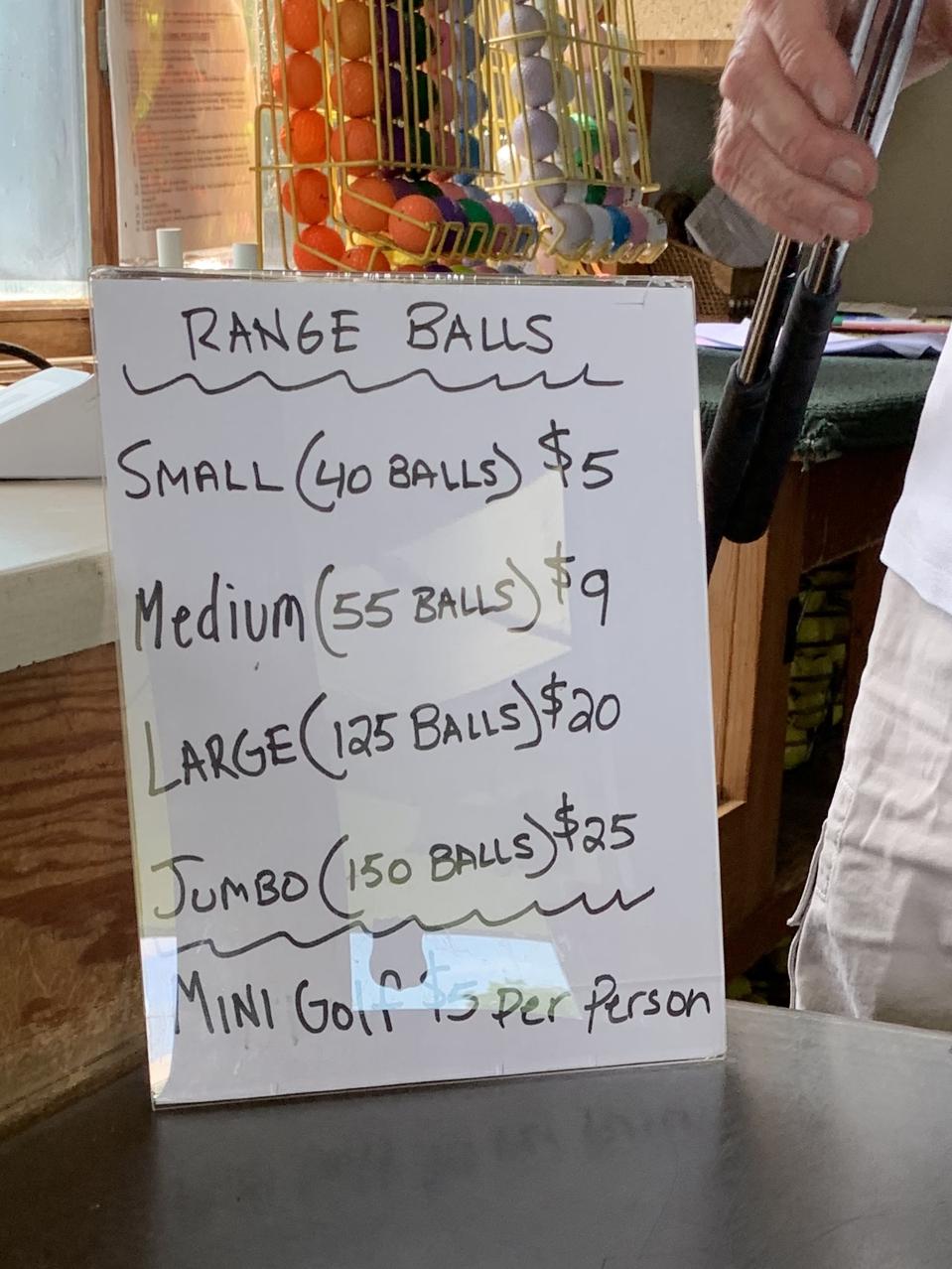 A sign depicts pricing for various-sized buckets of golf balls.