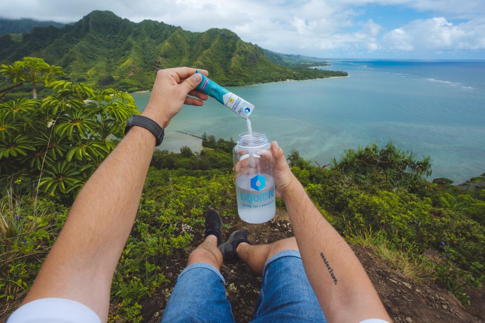 Pouring a hydration packet into a water bottle