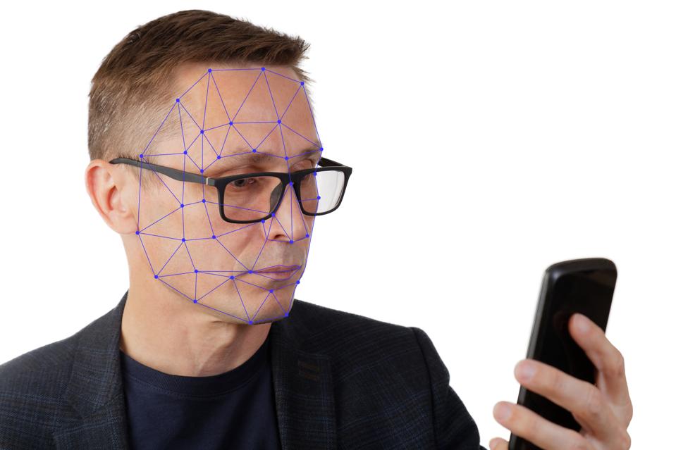 Portrait of man with smartphone using face ID recognition system.