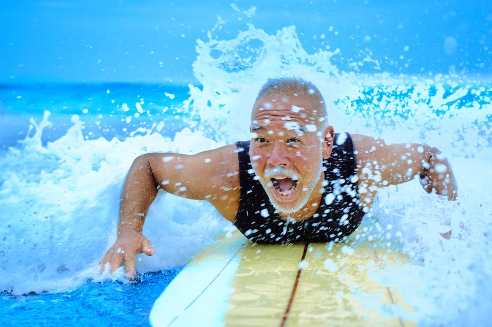 Surfer paddling with surfboard on Japanese beach in splash.