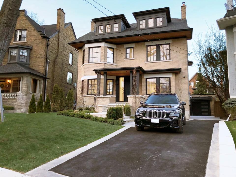 BMW in front of a large expensive home.