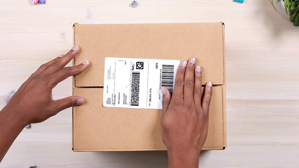 A cardboard box showing someone attaching a free shipping label.