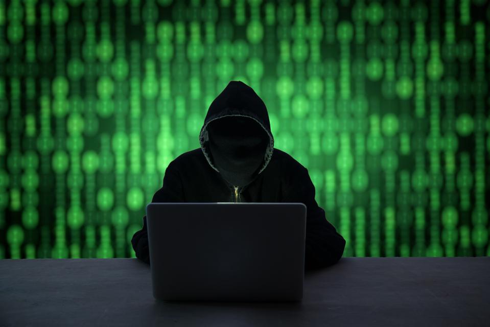 Hacker With Obscured Face Using Laptop At Desk