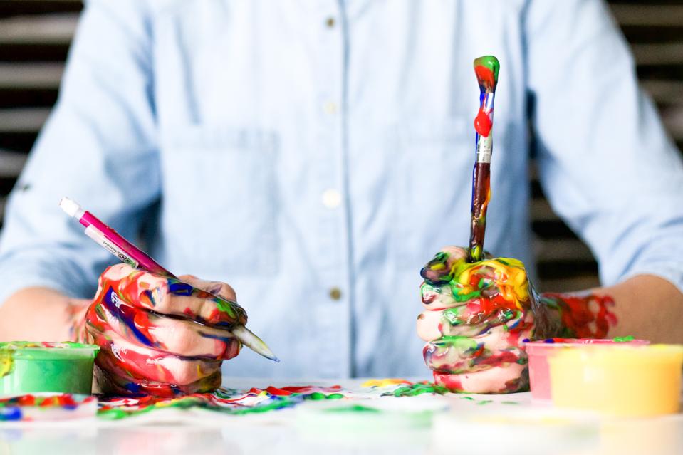 A marketer holds a pencil and paintbrush.