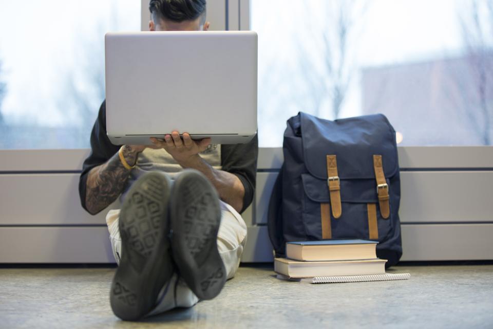 College student using laptop on floor