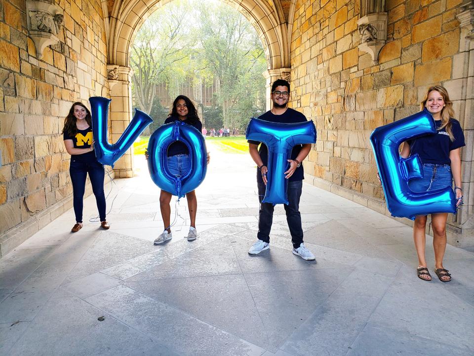 Michigan students stand with balloons which spell vote.