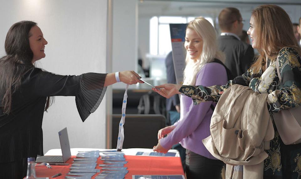 A woman handing a lanyard to another female.