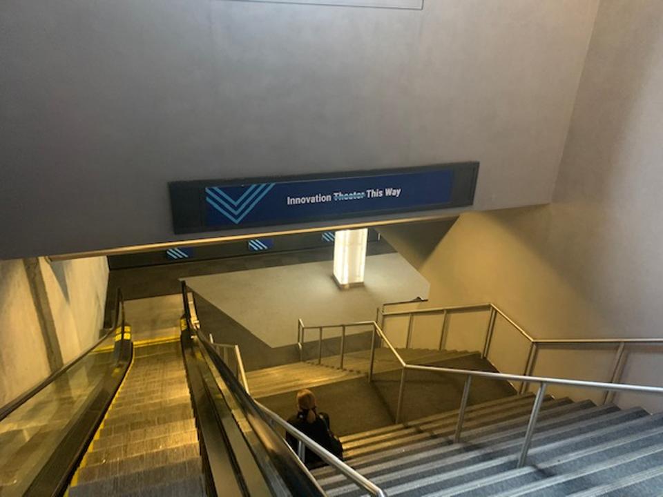 Photo of a staircase with a sign saying Innovation Theater This Way with Theater crossed out. Photo taken by Jules Miller at the CB Insights The Collective conference in New York, December 11, 2019