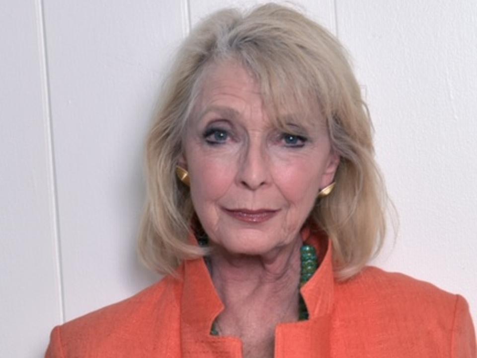 Headshot of Valentino in an orange suit jacket.