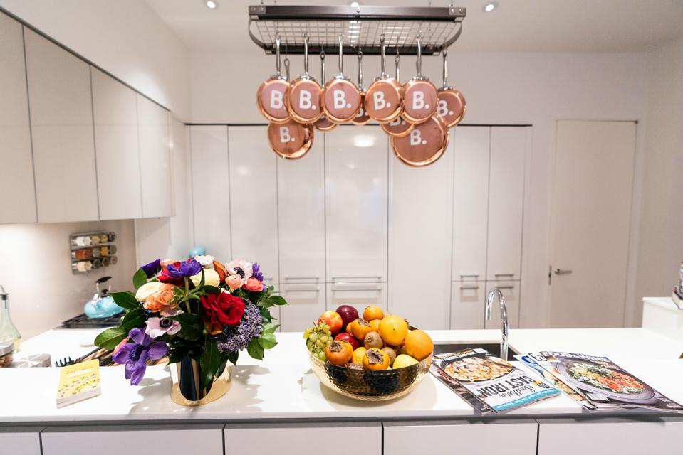 A kitchen with copper pots and pans hanging from a pot rack.