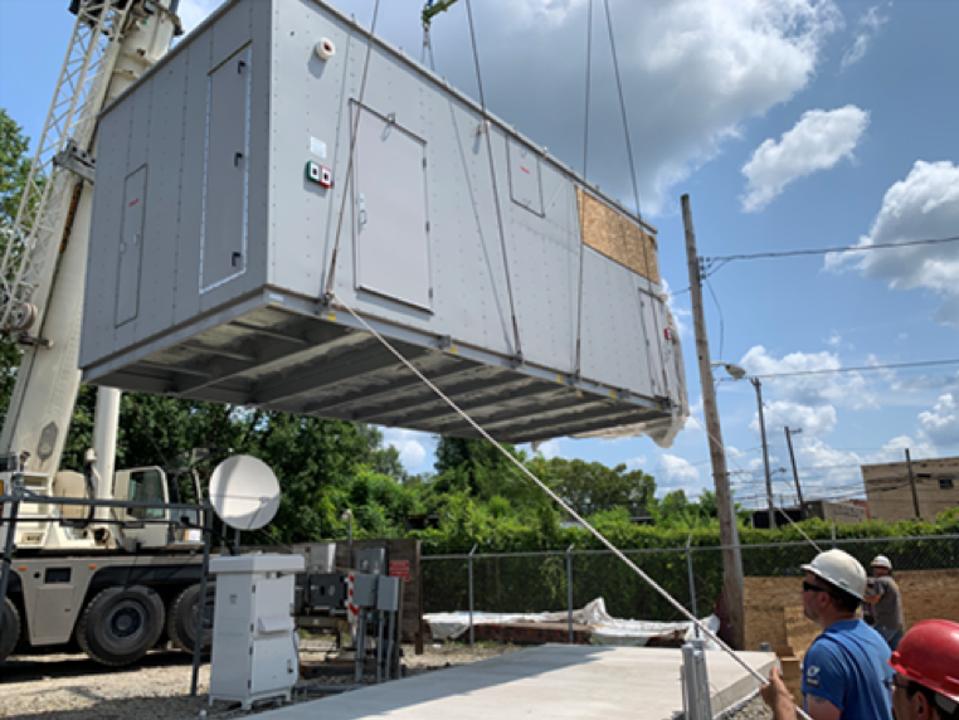 A Vapor Edge Module being lowered by crane onto the concrete slab