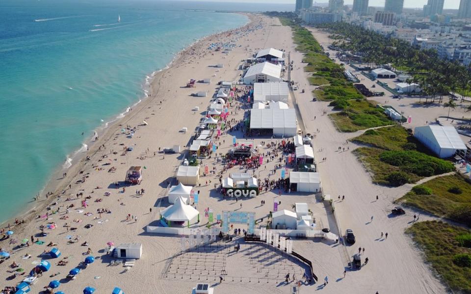 An aerial shot of various food and drink tents on the beach.