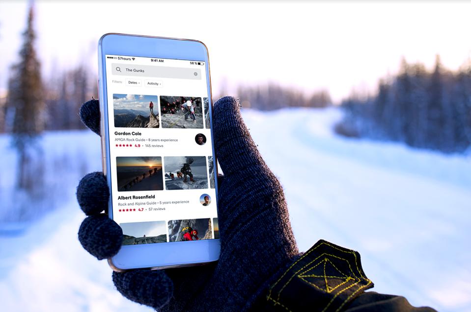 A gloved hand holding the 57Hours app on a phone