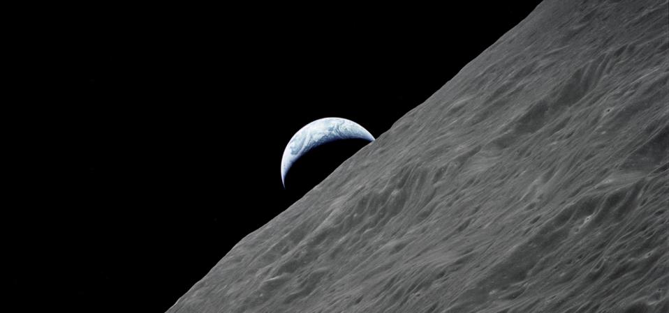The crescent Earth rises above the lunar horizon in this spectacular photograph taken from the Apollo 17 spacecraft in lunar orbit during final lunar landing mission in the Apollo program.