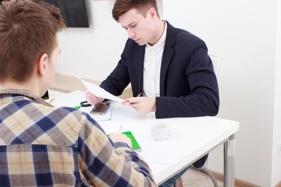Serious manager interviewing a male applicant in her office