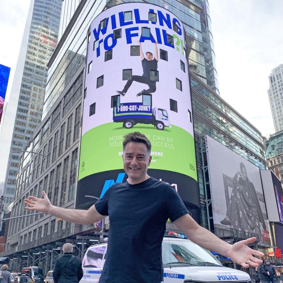 Brian Scudamore in front of aNYC billboard showing his book: WTF?! Willing to Fail.