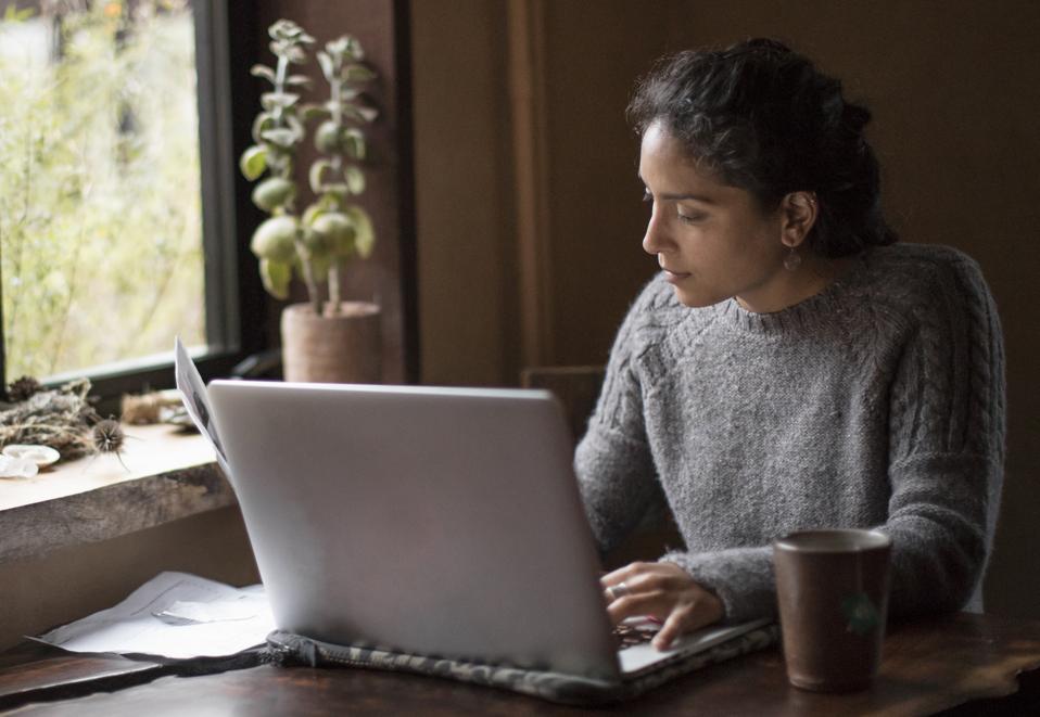 Young Woman University Student or Businesswoman Works from Home Using Laptop and Reference Papers