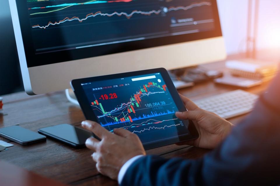 Businessman checking stock market on digital tablet and a desktop computer