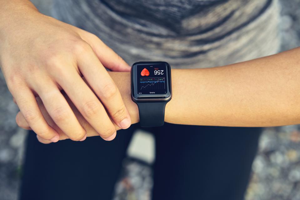 Woman checking the sports watch measuring heart rate and performance after running.