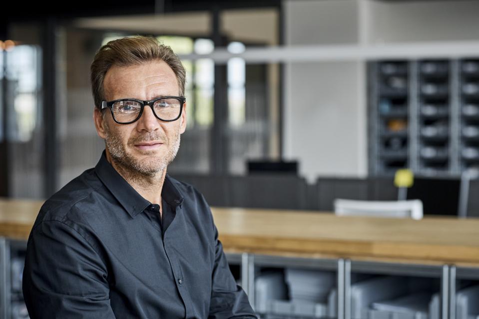 A bespectacled man sits in an empty room, full of ennui.
