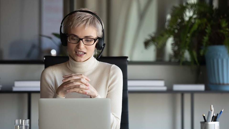 Lady in front of a laptop talking to a customer.