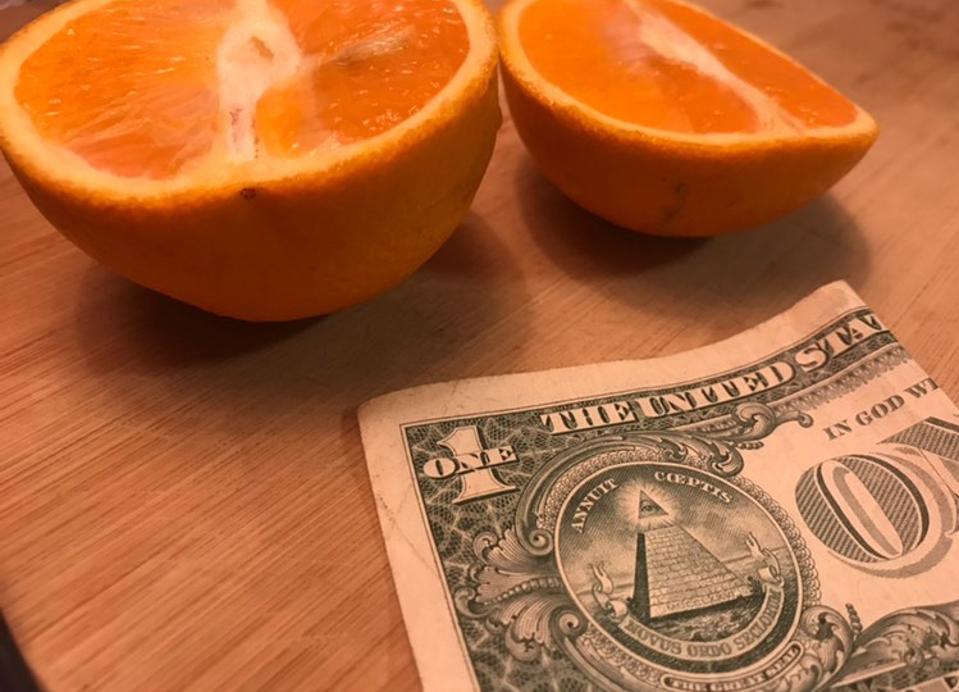 An orange split in half, and the US Dollar.